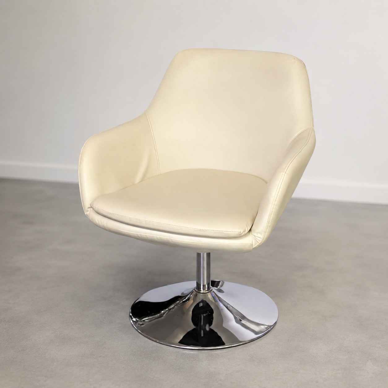 Poltrona girevole moderna con rivestimento in ecopelle color crema e base circolare in metallo cromato lucido, su sfondo neutro.