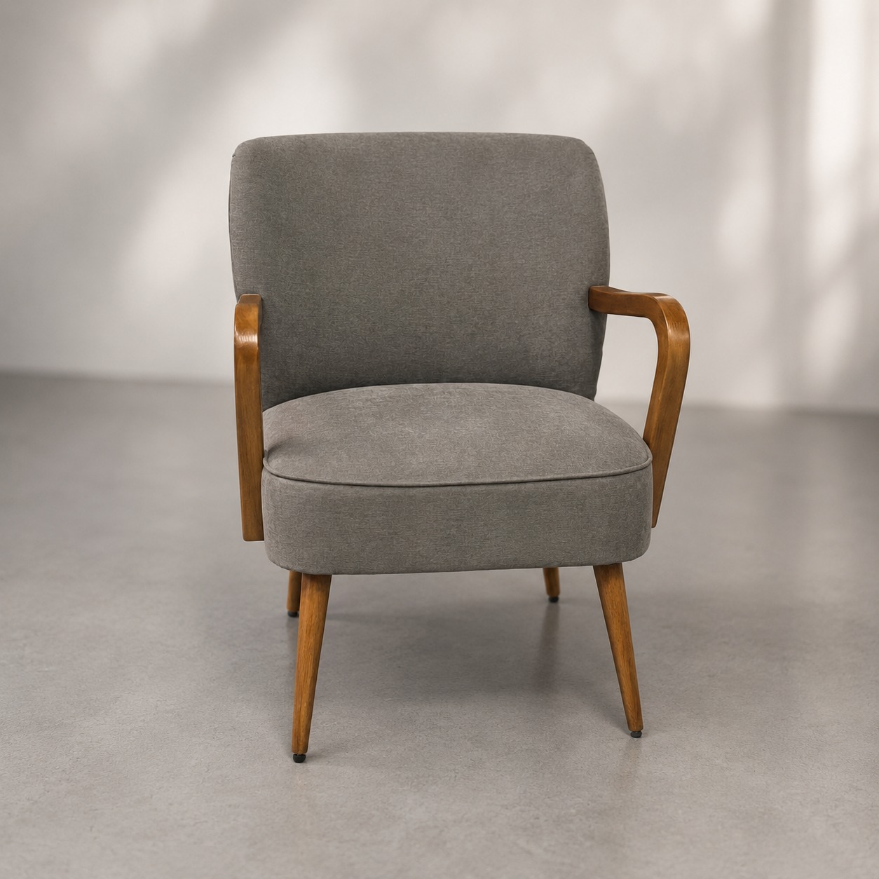 Poltrona vintage con rivestimento in tessuto grigio e struttura in legno chiaro, gambe affusolate e braccioli curvi.