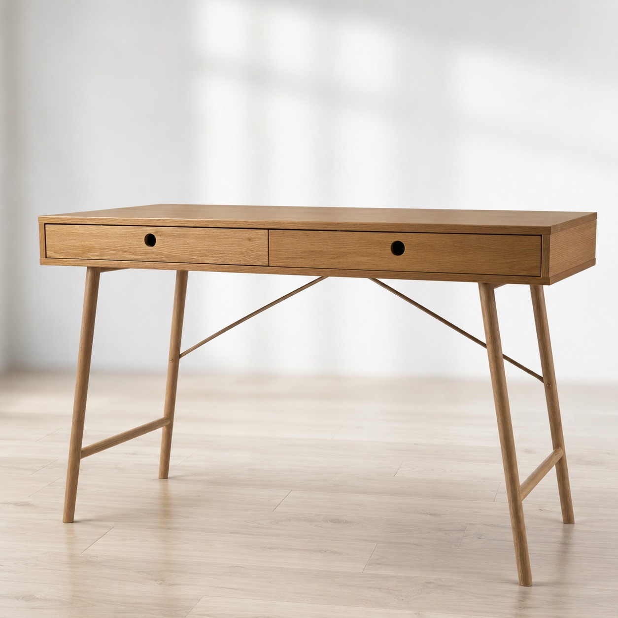 Scrivania moderna in legno di rovere chiaro con due cassetti e gambe affusolate, su pavimento in legno.