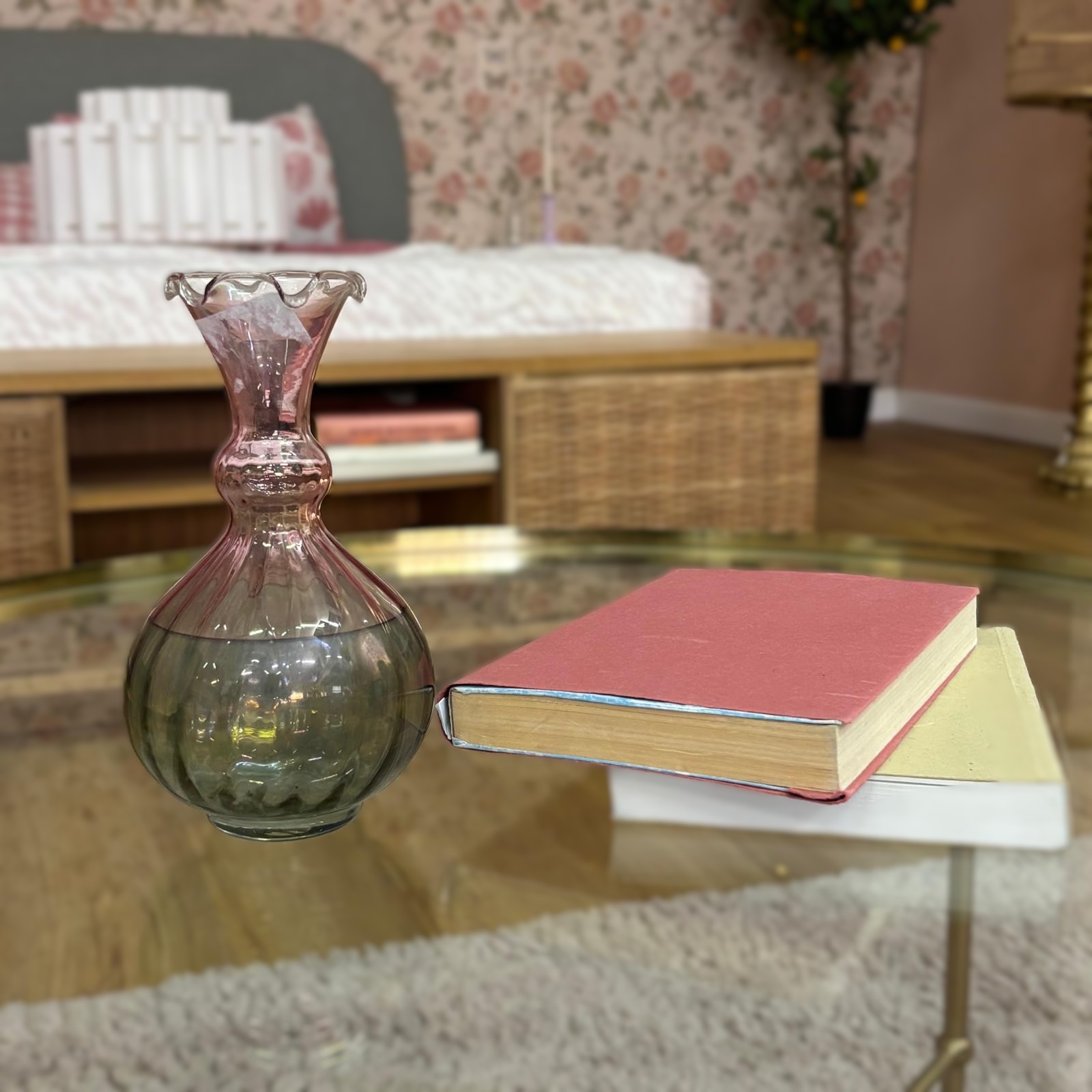 Vaso decorativo in vetro bicolore rosa e grigio fumé con bordo ondulato, affiancato da due libri antichi su un tavolino di vetro.