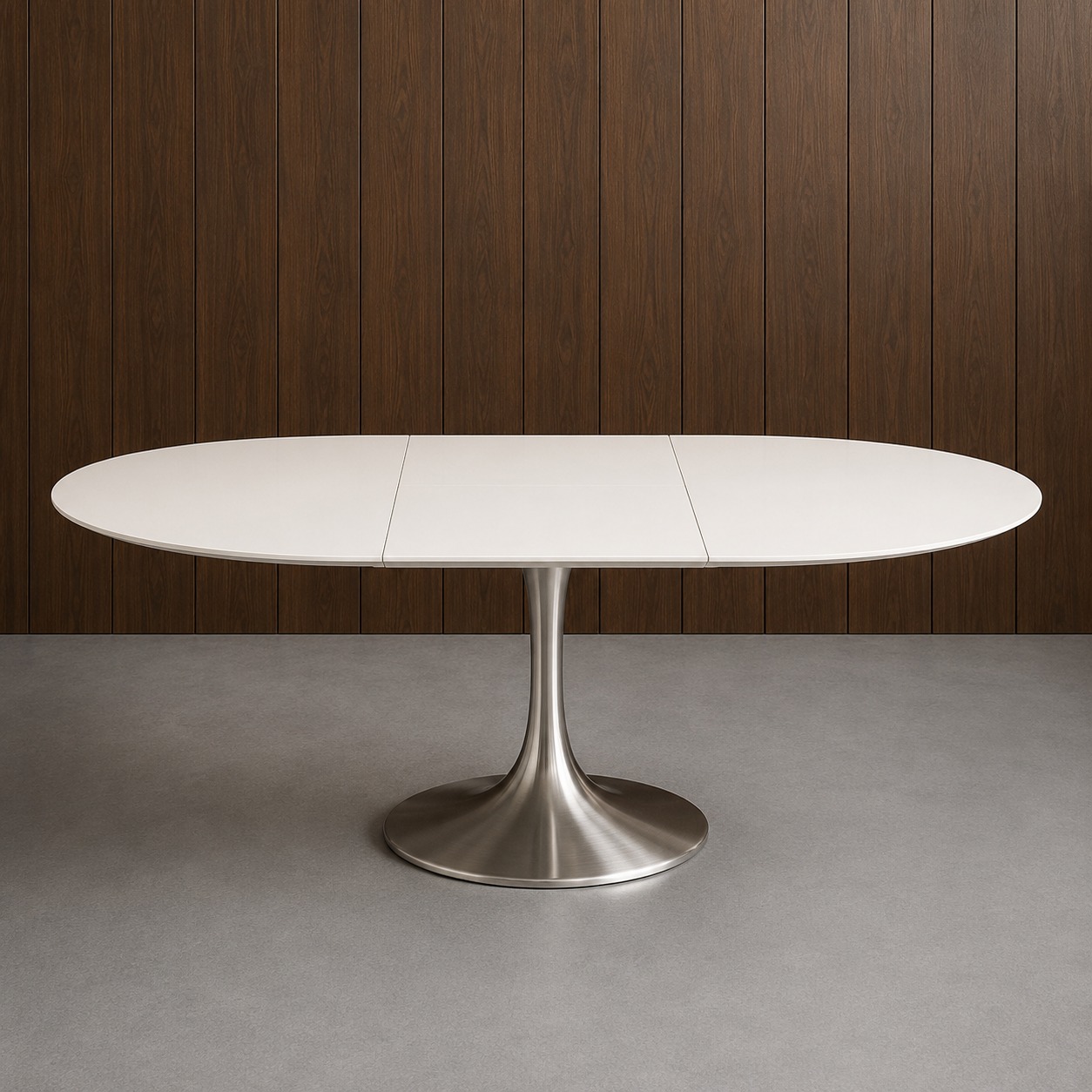 Tavolo ovale allungabile con piano bianco opaco e base a colonna in metallo spazzolato, su pavimento grigio con parete in legno scuro.